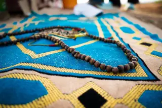 Ilustrasi: Untaian tasbih kayu diletakkan di atas sajadah berwarna biru bermotif.