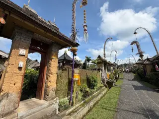 Ilustrasi: Jalanan desa tradisional Bali berhiaskan deretan penjor di bawah langit cerah berawan.