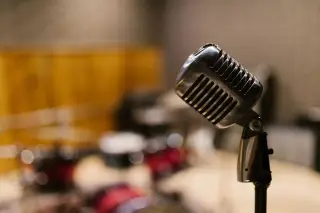 Ilustrasi: Mikrofon logam bergaya vintage di studio musik dengan latar buram.