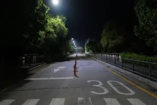 Ilustrasi: Jalan aspal sepi pada malam hari dengan marka angka 30 dan penerangan lampu jalan.