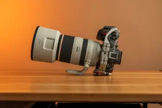 Ilustrasi: Sebuah kamera digital dengan lensa telefoto panjang diletakkan di atas meja kayu.