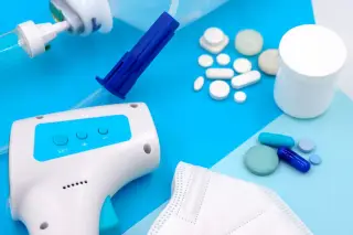 Ilustrasi: Termometer tembak, masker medis, dan aneka obat serta pil di atas latar biru.