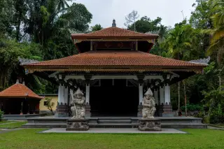 Ilustrasi: Bangunan pura berarsitektur Bali dengan dua patung penjaga di depannya.