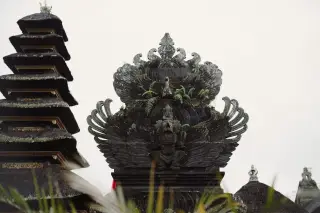 Ilustrasi: Ukiran batu hitam dan menara meru bertingkat pada kompleks pura di Bali.