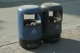 Ilustrasi: Dua tempat sampah pilah warna biru dan hitam di pinggir trotoar.
