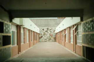 Ilustrasi: Lorong luar ruangan yang sepi di antara dua bangunan berdinding bata.