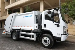Ilustrasi: Sebuah truk pengangkut sampah modern berwarna putih terparkir di pinggir jalan paving.