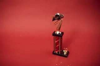 Ilustrasi: Sebuah piala berwarna emas berdiri di atas latar belakang merah polos.