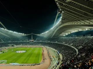 Ilustrasi: Suasana stadion sepak bola megah yang dipadati penonton di bawah sorotan lampu malam hari.