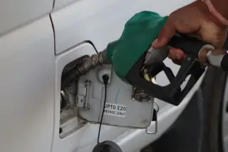 Ilustrasi: Tangan seseorang memasukkan nozel bahan bakar ke tangki mobil putih.