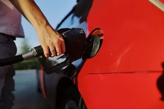 Ilustrasi: Seseorang mengisi bahan bakar ke tangki mobil merah dengan nozel bensin.