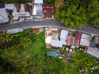 Ilustrasi: Pemandangan udara jalan beraspal di tepi persawahan terasering dan atap perumahan.