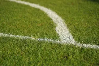 Ilustrasi: Garis putih penanda lapangan di atas rumput hijau.