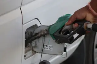 Ilustrasi: Seseorang mengisi bahan bakar ke tangki mobil putih menggunakan nozel bensin.