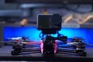 Ilustrasi: Drone balap FPV yang dipasangi kamera aksi di atas meja dengan latar lampu biru.