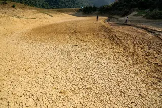 Ilustrasi: Hamparan tanah kering dan retak dengan dua orang berjalan di kejauhan.