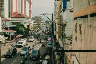 Ilustrasi: Suasana lalu lintas perkotaan yang ramai dengan mobil, sepeda motor, dan pejalan kaki di jalan raya.