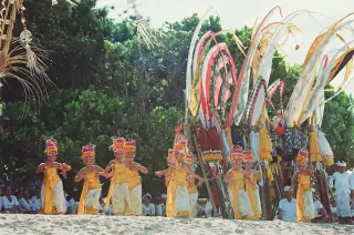 Ilustrasi: Sekelompok penari Bali berpakaian adat kuning menari di pantai berpasir.