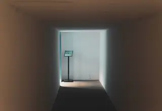 Ilustrasi: Lorong bangunan yang sepi dengan pencahayaan lembut dan papan tanda kecil di ujungnya.