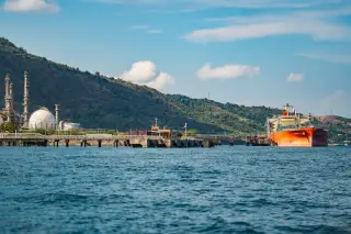 Ilustrasi: Kapal tanker bersandar di dermaga fasilitas industri minyak dekat perbukitan.