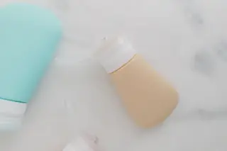 Ilustrasi: Botol-botol kecil perlengkapan mandi berbahan silikon di atas permukaan marmer.