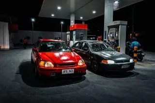 Ilustrasi: Dua mobil sedan terparkir di area pengisian bahan bakar SPBU pada malam hari.