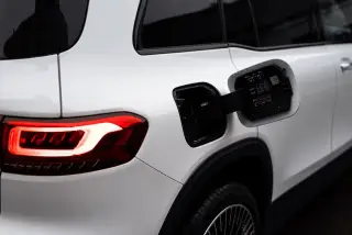 Ilustrasi: Tampak dekat bagian belakang mobil listrik putih dengan soket pengisian daya terbuka.