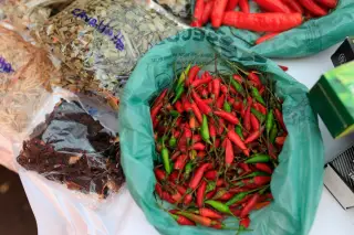 Ilustrasi: Cabai rawit merah dan hijau di dalam kantong plastik hijau di samping rempah-rempah kering.