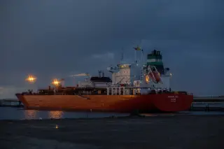 Ilustrasi: Sebuah kapal tanker besar bersandar di pelabuhan pada malam hari dengan lampu menyala.