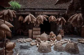Ilustrasi: Deretan aneka kerajinan anyaman bambu tertata di halaman depan sebuah bangunan tua.