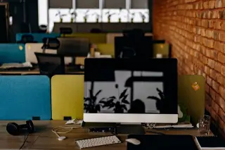 Ilustrasi: Komputer desktop di atas meja kantor yang kosong dengan latar dinding bata.