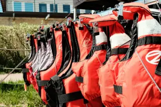 Ilustrasi: Deretan jaket pelampung warna merah tergantung di luar ruangan.