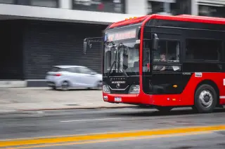 Ilustrasi: Sebuah bus kota berwarna merah dan hitam melaju di jalan raya perkotaan.