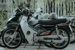 Ilustrasi: Deretan sepeda motor terparkir di luar ruangan dengan helm di atas jok.