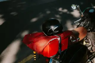 Ilustrasi: Helm hitam diletakkan di atas bagian belakang sepeda motor yang terparkir.
