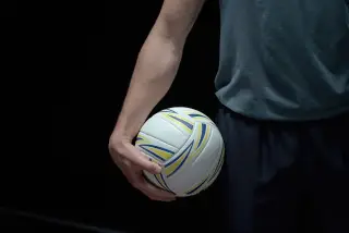 Ilustrasi: Seseorang memegang bola voli dengan latar belakang gelap.
