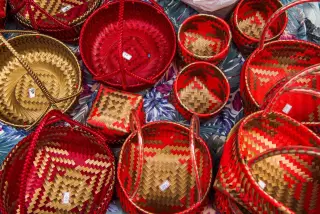 Ilustrasi: Deretan keranjang anyaman tangan berwarna merah dan emas dengan label harga kecil.